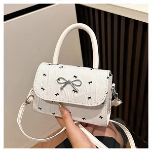 Vue détaillée du mini sac blanc texturé avec imprimé nœuds noirs et boucle métallique argentée