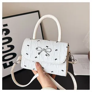 Détail d'un mini sac blanc avec imprimé nœuds noirs et fermoir en métal argenté