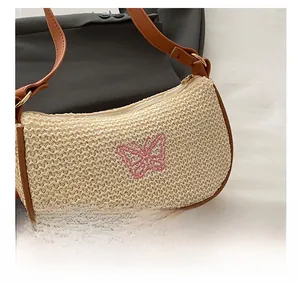 Detailansicht der gewebten cremefarbenen Strohtasche mit rosa Schmetterlingsstickerei und Lederband