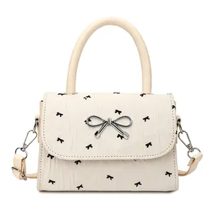 Sac à main blanc crème avec motifs de nœuds noirs et fermoir métallique argenté