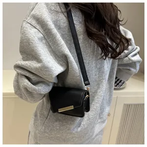 Détail d'un petit sac noir à boucle dorée porté par un mannequin en studio