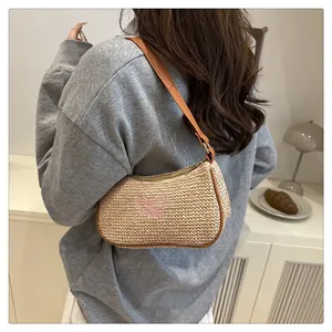 Detailansicht der Stroh-Achseltasche mit rosa Schmetterlingsstickerei und Lederriemen