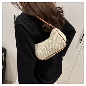 Detail der Sommer-Stroh-Hobo-Tasche mit beigem Webmuster und braunem Lederriemen am Model