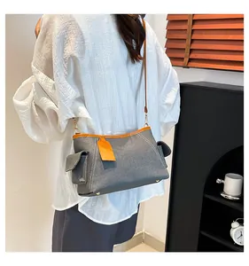 Details der dunkelgrauen Jeans-Umhängetasche mit orangefarbenem Lederbesatz und Seitentaschen