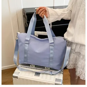 Dettaglio della borsa da viaggio azzurra in nylon resistente su una valigia bianca