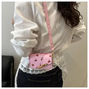 Roze mini crossbodytas met kersenprint en gouden metalen detail bij een model