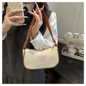 Detail der Strohtasche mit rosa Schmetterlingsstickerei und Leder-Schultergurt