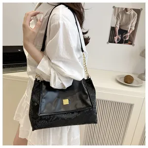Detail of black crossbody bag with smooth leather and snake skin texture stitching