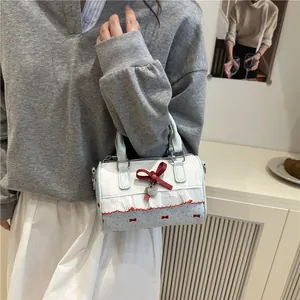 Blue and white cylindrical handbag with red bows, lace trim, and a heart charm