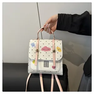 Detail eines weißen gepunkteten Mini-Rucksacks mit bunten Patches und rosa Riemen