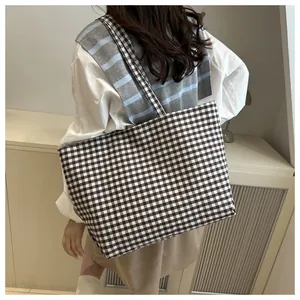 Detail of checkered canvas tote bag showing large capacity on model's shoulder