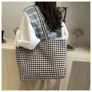 Side view of large gingham canvas tote bag worn on shoulder in a cozy home setting