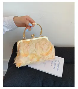 Macro detail of cream floral clutch bag featuring 3D fabric petals and gold hardware