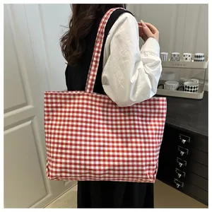 Detail of red and white gingham canvas tote bag with durable shoulder straps in home setting