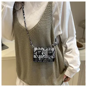 Dettaglio della mini borsa a tracolla pitonata con doppie fibbie indossata dalla modella