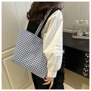 Detailed side view of blue and white gingham canvas tote bag worn by a model