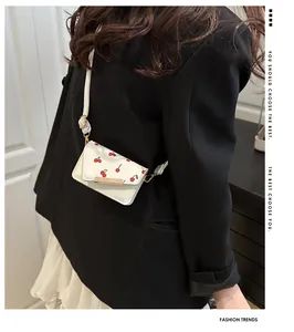 Detail van de witte mini crossbodytas met kersenprint en gouden metalen sluiting