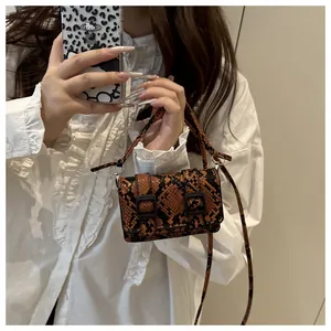 Dettaglio texture pitonata e doppia fibbia su una mini borsa a tracolla marrone