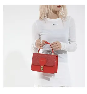 Detail of red leather handbag featuring glitter flap and golden fashion turn-lock