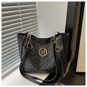 Détail d'un sac bandoulière noir à monogramme avec logo M doré et bandoulière chaîne