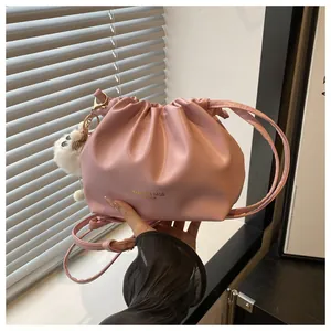 Detalle de bolso saco rosa con cordón, colgante de peluche y letras doradas