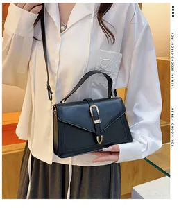 Detail view of black minimalist leather crossbody bag with elegant gold V-shape clasp