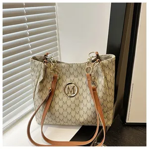 Détail du sac cabas vintage avec imprimé monogramme M et logo en métal doré brillant