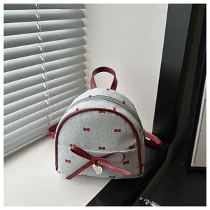 Detailopname van lichtblauwe mini-rugzak met rode strik en hartvormige metalen hanger decor