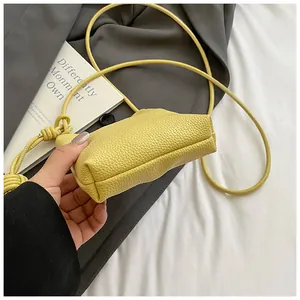 Dettaglio mini borsa a tracolla in pelle gialla con cinturino a nodo e fondo tondo