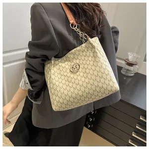 Vue latérale du sac fourre-tout beige avec bandoulière en cuir brun et chaîne dorée