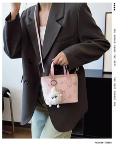 Pink printed leather bucket bag with cute motifs and plush charm worn by a model
