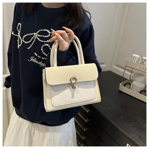 Detail of cream crossbody bag featuring a golden horseshoe clasp and woven texture