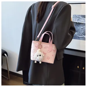 Detail of pink embossed leather bucket bag with cartoon patterns and plush charm