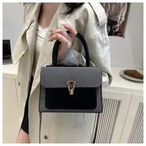 Close-up of a stylish minimalist crossbody bag with gold buckle and textured contrast material