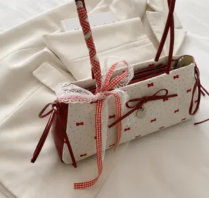 Detail of red gingham ribbon bow and silver heart pendant on a pleated tote bag