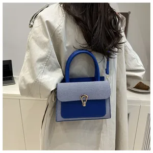 Detail of blue striped crossbody bag with gold buckle worn by model in a trench coat