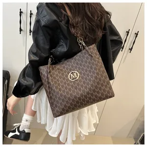 Détail latéral du cabas marron à monogramme avec chaîne porté par un modèle