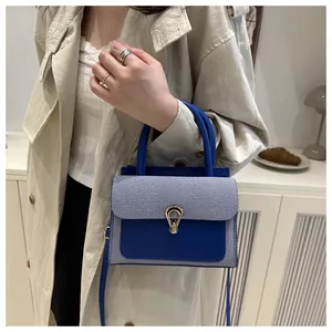 Detail view of royal blue leather crossbody bag with a round handle and modern clasp