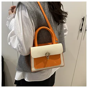 Detail view of the retro textured woven fabric and orange leather flap on small square bag