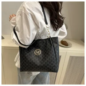 Détail du sac cabas noir avec motif M imprimé et chaîne en métal doré