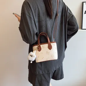 Contrast color embossed crossbody bucket bag with plush charm shown on model