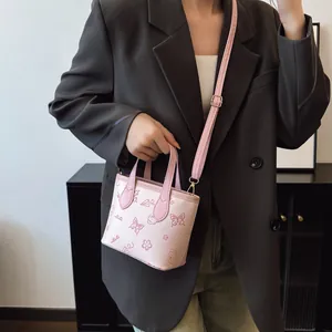 Pink mini tote bag with cartoon patterns and adjustable strap shown on office outfit