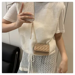 Detalle de bolso bandolera marrón claro con relieve geométrico y correa de cadena dorada
