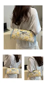 Detailed embroidery of yellow roses on an off-white shoulder bag with blue ribbon bows