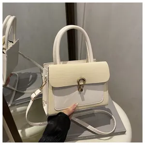 Close-up of beige crossbody bag with textured flap and elegant gold metal buckle closure