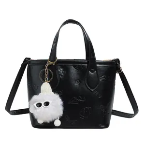 Chic black embossed crossbody bucket bag with fun plush pendant and shoulder strap