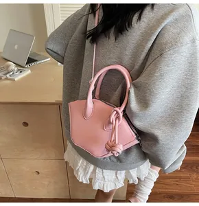 Sac bandoulière trapèze rose chic avec détail noué porté par un mannequin dans un studio