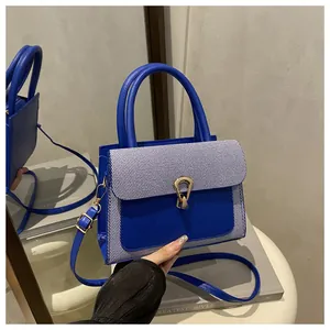 Detail of royal blue small square bag with striped flap and golden horseshoe buckle