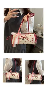 Detail of a pleated canvas underarm bag with red bows and a heart-shaped metal pendant