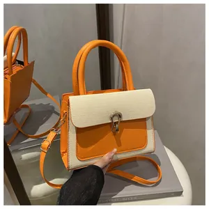 Detail of orange faux leather crossbody bag featuring textured weave flap and horseshoe buckle